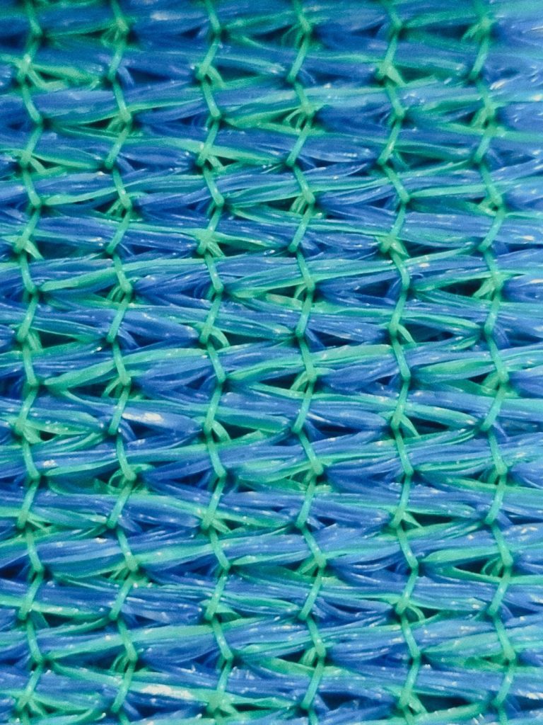 A close-up macro shot of a blue and green synthetic woven fabric mesh